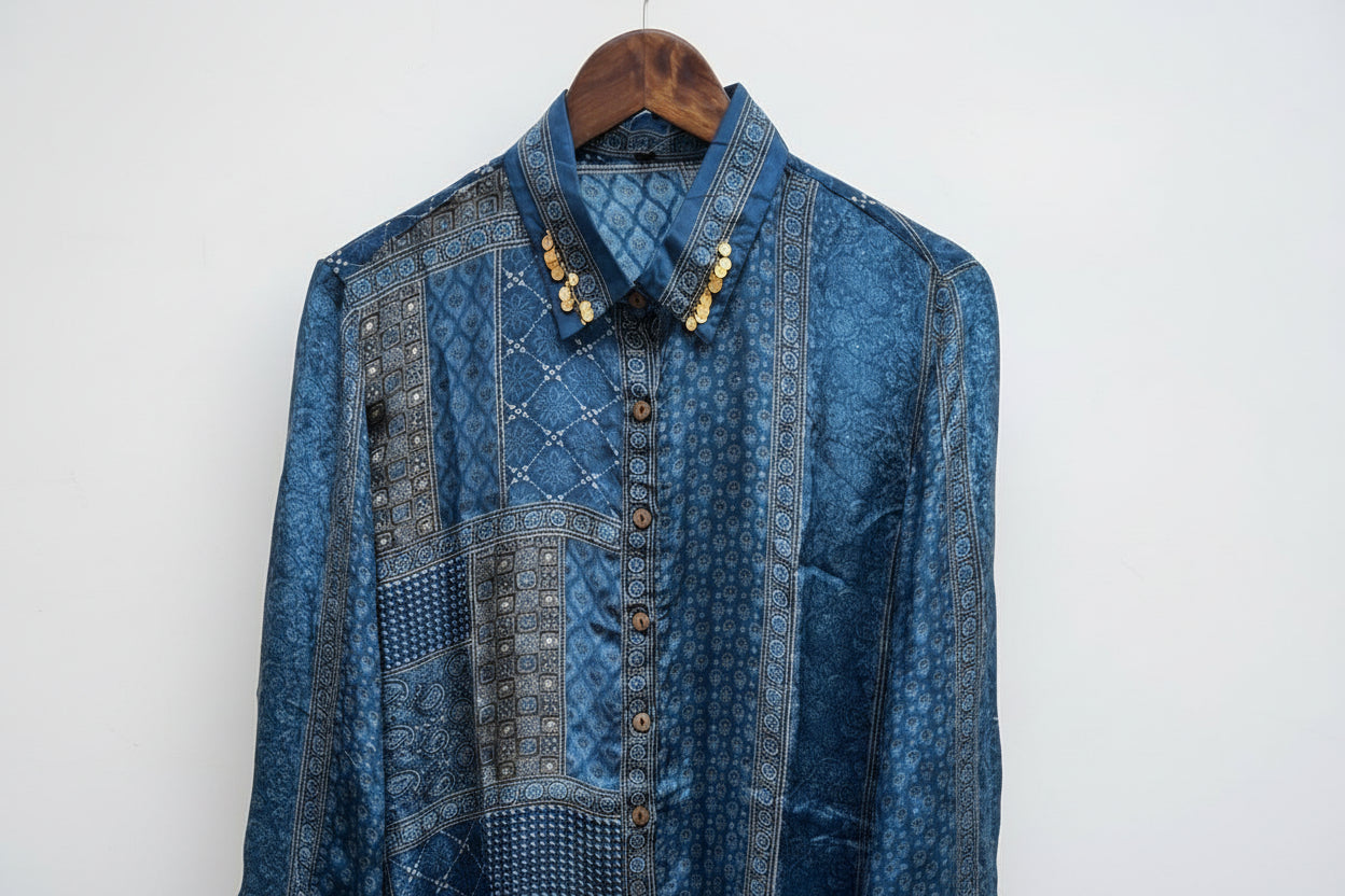 blue ajrakh printed shirt on a wooden hanger on a white textured wall as the  background.
